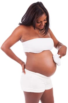 Young pregnant indian woman holding baby shoes, isolated on white background
