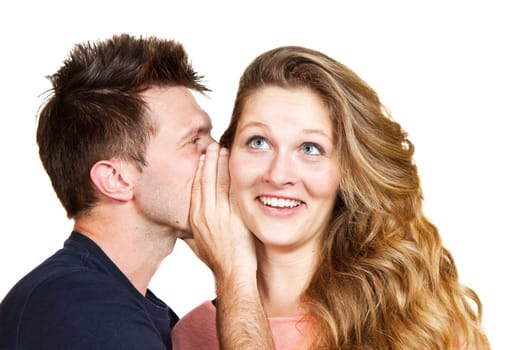 Portrait of a handsome young man whispering a secret to a cute woman against white