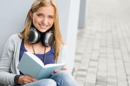 Woman reading book outside of school young happy smiling student