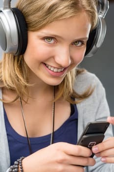 Teenage girl checking her mobile phone smiling looking at camera