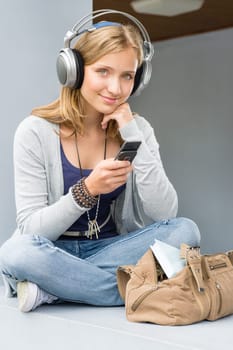Young woman holding her mobile phone sitting wall outdoor