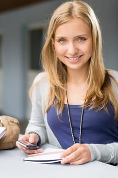 Teenage woman with notes and cellphone student young happy smiling