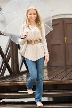 Woman stepping down the stairs with umbrella happy smiling rain