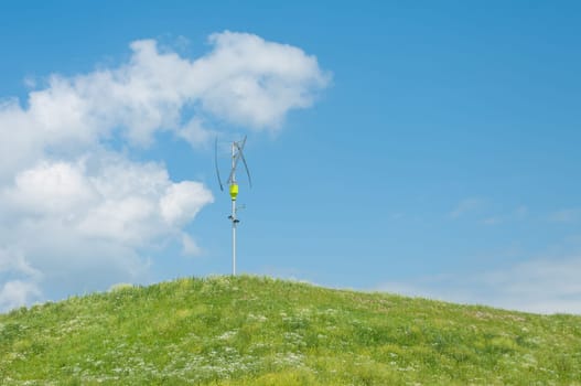 small vertical axis wind turbine on a green hill