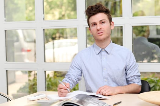 Young adult man writing notes with pen