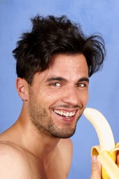 Smiling 30 years old man with banana over a blue background