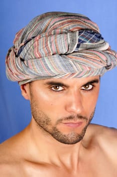 Sexy 30 years old man with turban portrait over a blue background