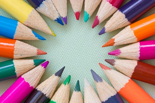 Circle of colored pencils on the blue background