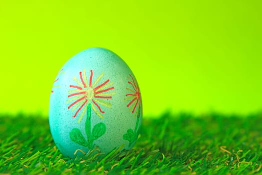 Easter decoration made of single green Easter egg with floral motif painted in artificial grass