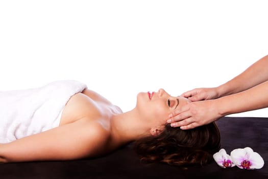 Beautiful happy peaceful sleeping woman at a spa, laying on massage table with eyes closed wearing a towel getting a facial massage, isolated.