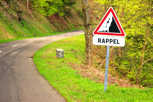 Country road in the Vosges,Alsace,France with the French road sign "Steinschlaggefahr"" and the additional sign ""RAPPEL"""