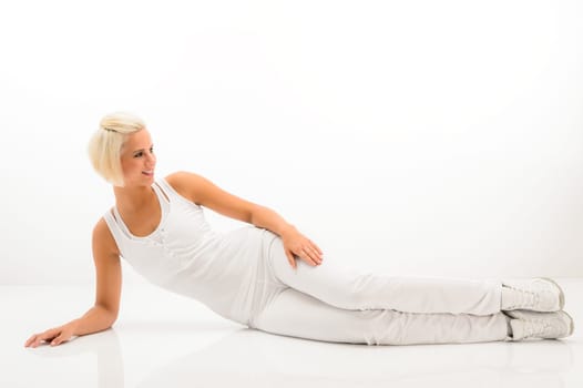 Woman stretching her body fitness exercise lying on white floor