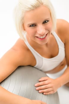 Smiling woman exercising on fitness ball on white background