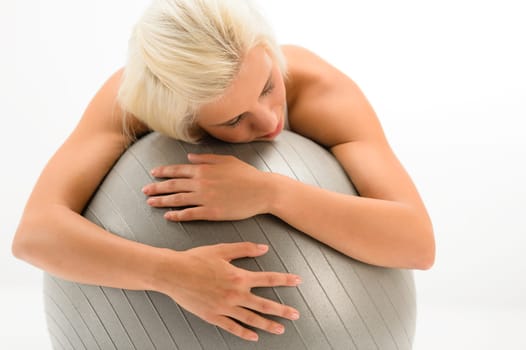 Exhausted sport woman resting on fitness ball on white background