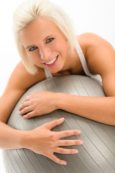 Smiling woman exercising on fitness ball on white background