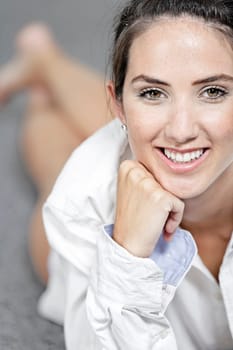 Beautiful young woman in a white shirt lying on her living room floor