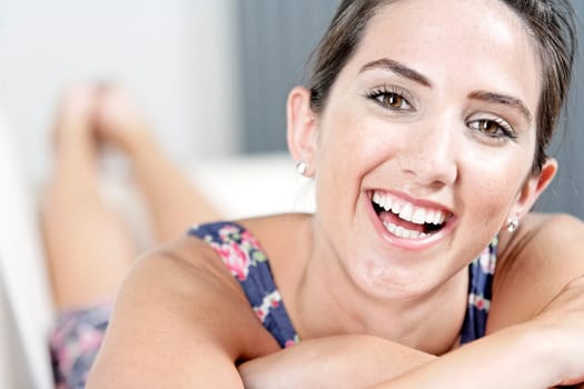 Beautiful young woman wearing a blue summer dress resting on her sofa at home