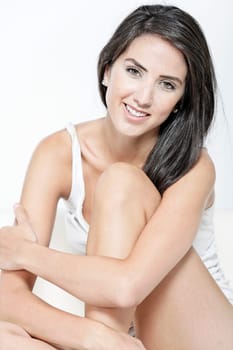 Beautiful sexy woman in white vest top sitting on a white sofa relaxing
