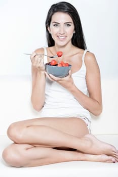 Beautiful young woman enjoying fresh fruit for breakfast at home