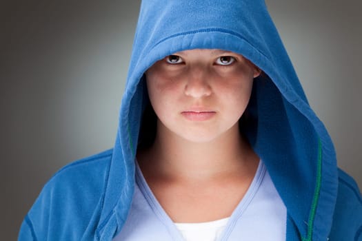 Studio portrait of a serious looking girl in a blue hooded jacket