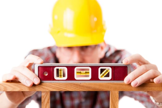 A construction worker using a level on a woodworking project