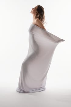 A couple celebrates the beauty of pregnancy as the woman poses elegantly in a flowing dress.