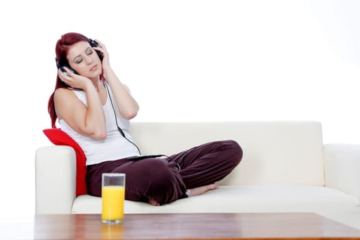 Happy smiling young woman listening to music at home on headphones
