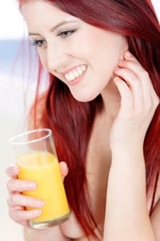 Beautiful woman drinking fresh Orange juice on her sofa at home