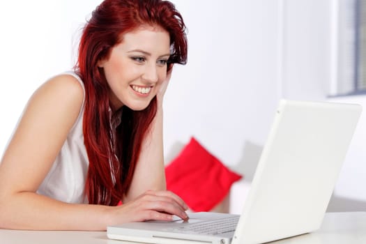 Happy young woman using a laptop at home