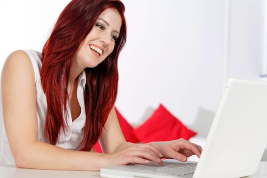 Happy young woman using a laptop at home