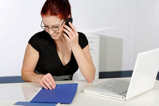 Beautiful young woman talking on her mobile phone at work