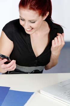Professional young woman receiving good news on her mobile at work