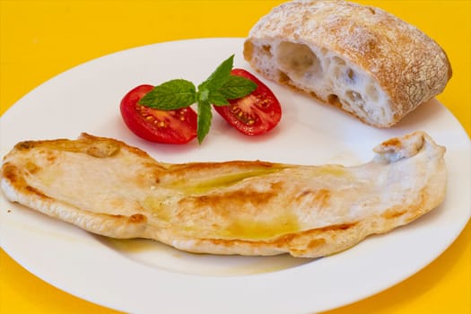 Turkey breast, presented in dish with tomato and rustic bread, mint ornament.