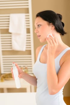 Young woman in bathroom clean face make-up removal looking aside