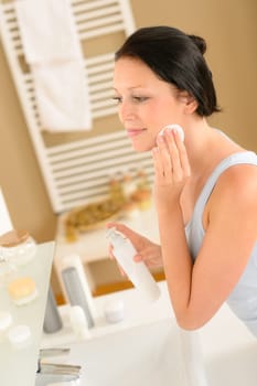 Young woman in bathroom clean face make-up removal looking mirror