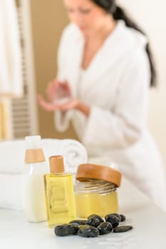Close-up body care products in bathroom with woman in background