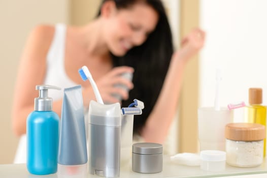 Bathroom shelf with beauty and hygiene products woman in background