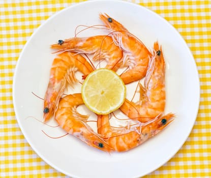 Pile of cooked and peeled shrimp. Detail of the heads and eyes of this seafood. Presented on plate with lemon