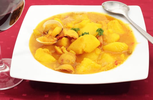 dish of boiled potatoes with clams squid and fish accompanied by wine