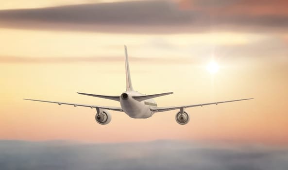 A commercial Jet flying high above the clouds into the sunset.