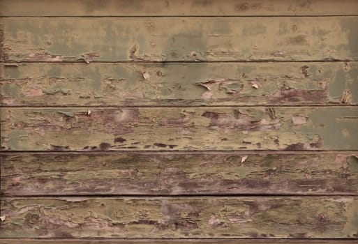 Distressed wood planks on an aged building showing blistered paint and wood grain