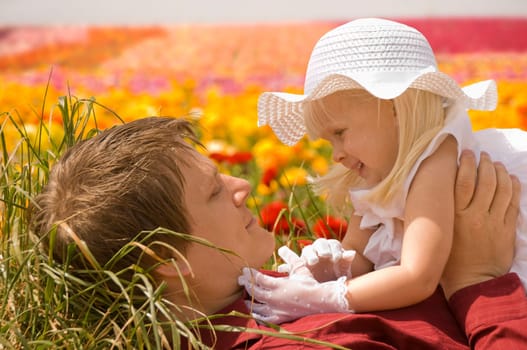Father and young daughter lying in a field of flowers