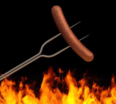 hot dog on a long fork over a fire