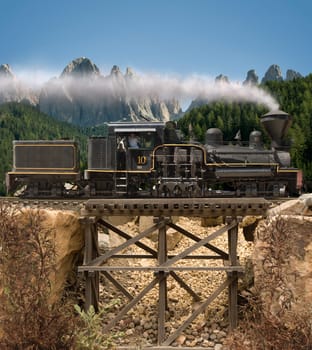 Steam locomotive going over a wooden trestle bridge with mountains in the background