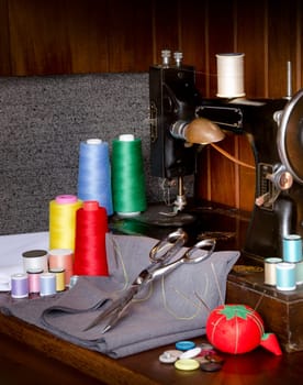 Retro sewing machine with sewing paraphernalia including thread, fabric, sewing needles, pin cushion, buttons scissors and thimble