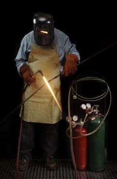 Person in protective welding gear heating a piece of metal