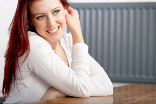 Beautiful young woman resting on a coffee table in front of sofa at home.