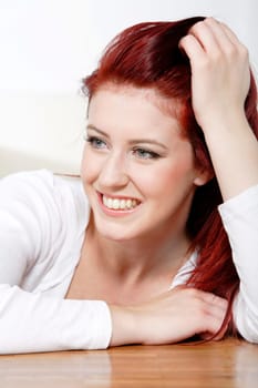 Beautiful young woman resting on a coffee table in front of sofa at home.