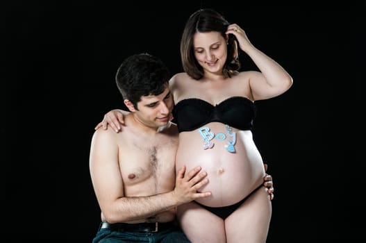 Portrait of young couple looking at baby belly and smiling