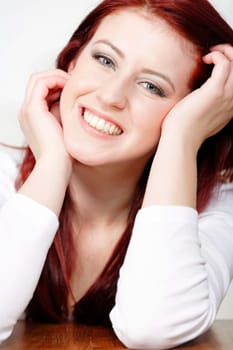 Beautiful young woman resting on a coffee table in front of sofa at home.